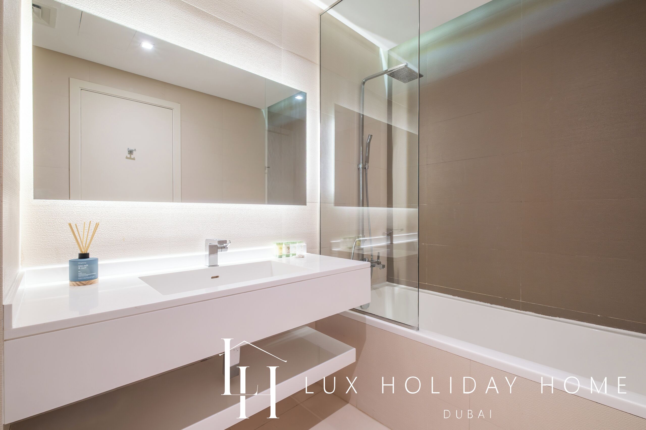 A modern bathroom with a large mirror, two sinks, and a glass-enclosed shower.