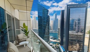 A modern hotel room with a balcony overlooking a cityscape, including a marina and high-rise buildings. - LUX  The West Avenue Dubai Marina Suite (Dubai)