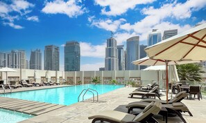 A rooftop pool area with lounge chairs and umbrellas, overlooking a city skyline. - LUX  The West Avenue Dubai Marina Suite (Dubai)