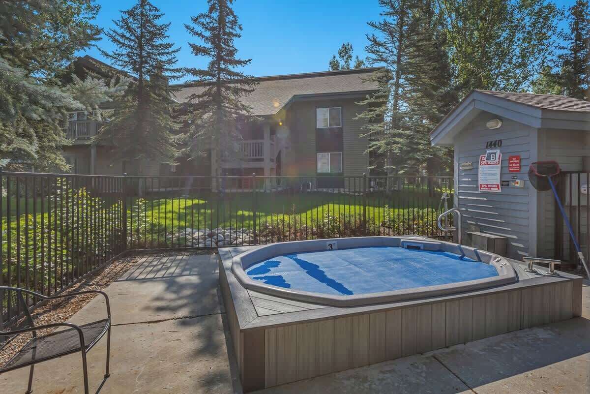 Un jardin avec un jacuzzi, un espace clôturé et un petit abri de jardin.