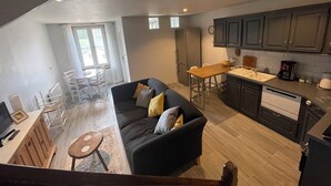 Una cocina moderna con armarios oscuros, una mesa de comedor de madera y un sofá negro con cojines.
