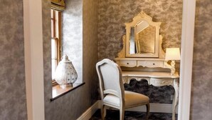 A room with a vanity, a chair, a mirror, and a lamp. - The Coach House (Reynoldston)
