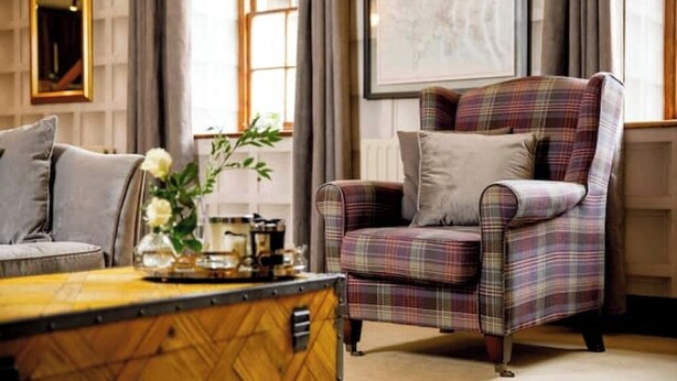 A cozy living room with a plaid armchair, a sofa, and a coffee table. - The Coach House (Reynoldston)