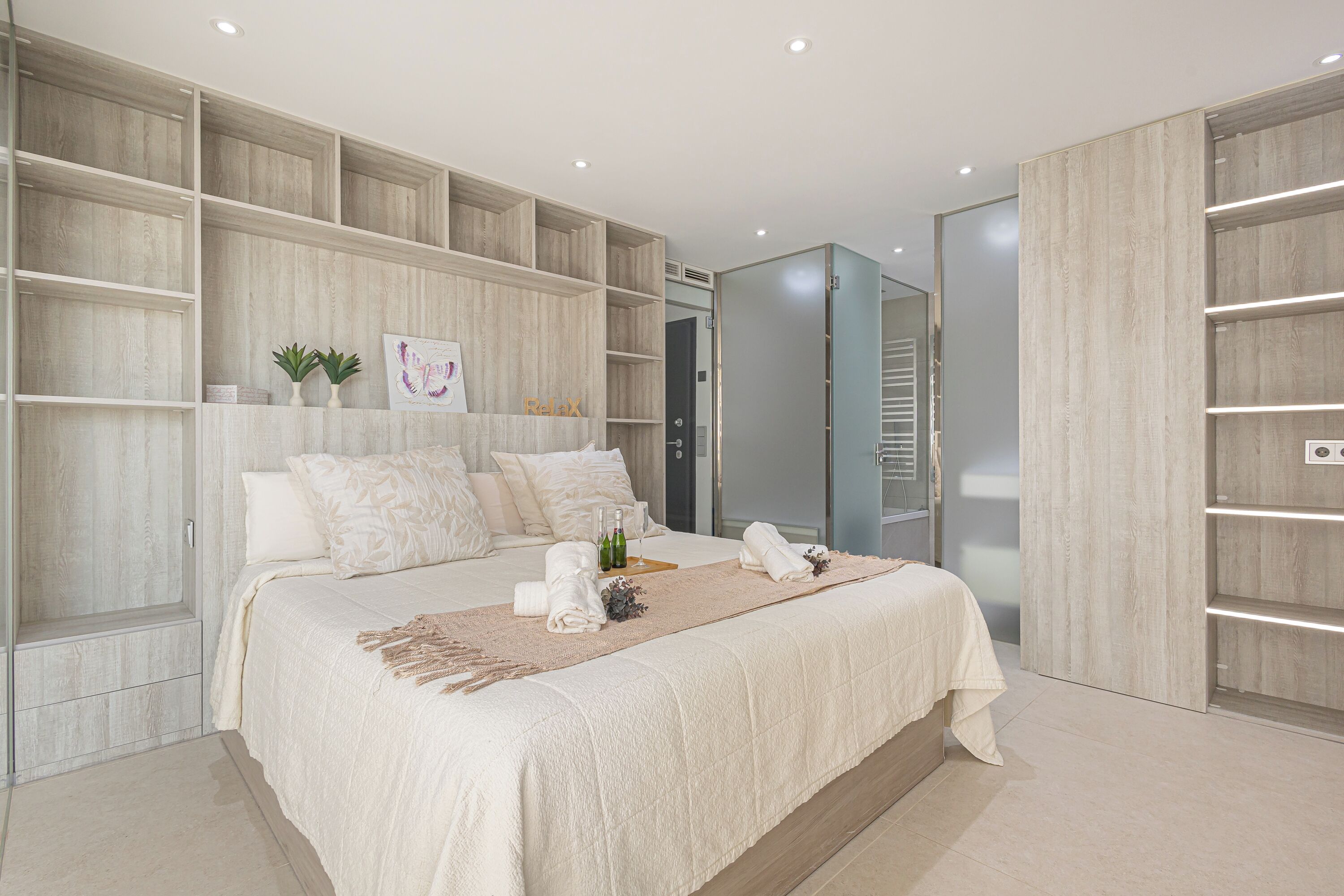 Een moderne slaapkamer met een groot bed, inbouwkasten en een inloopkast.