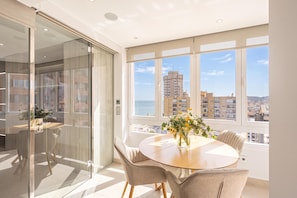 Un espace repas moderne avec une table ronde, des chaises et une vue sur la ville grâce à de grandes fenêtres.