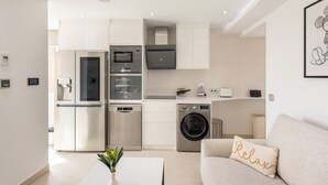 Une cuisine moderne équipée d’appareils électroménagers en acier inoxydable, d’un four encastré et d’un lave-linge.