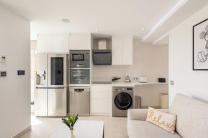A modern kitchen with stainless steel appliances, a built-in oven, and a washing machine. - Luxury Beachfront Suite Fuengirola for 2 (Fuengirola)