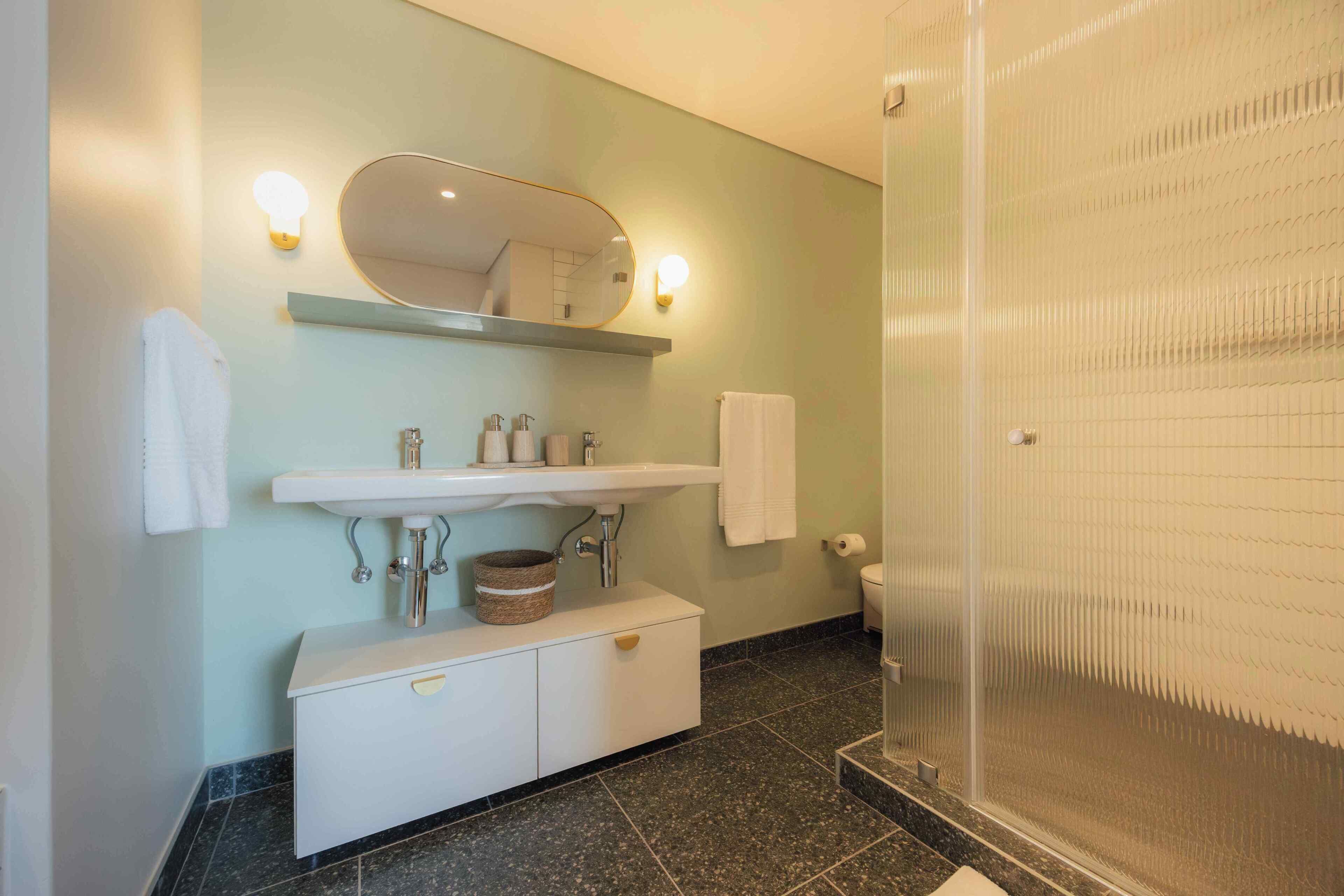 A bathroom with a white sink, mirror, and shower.
