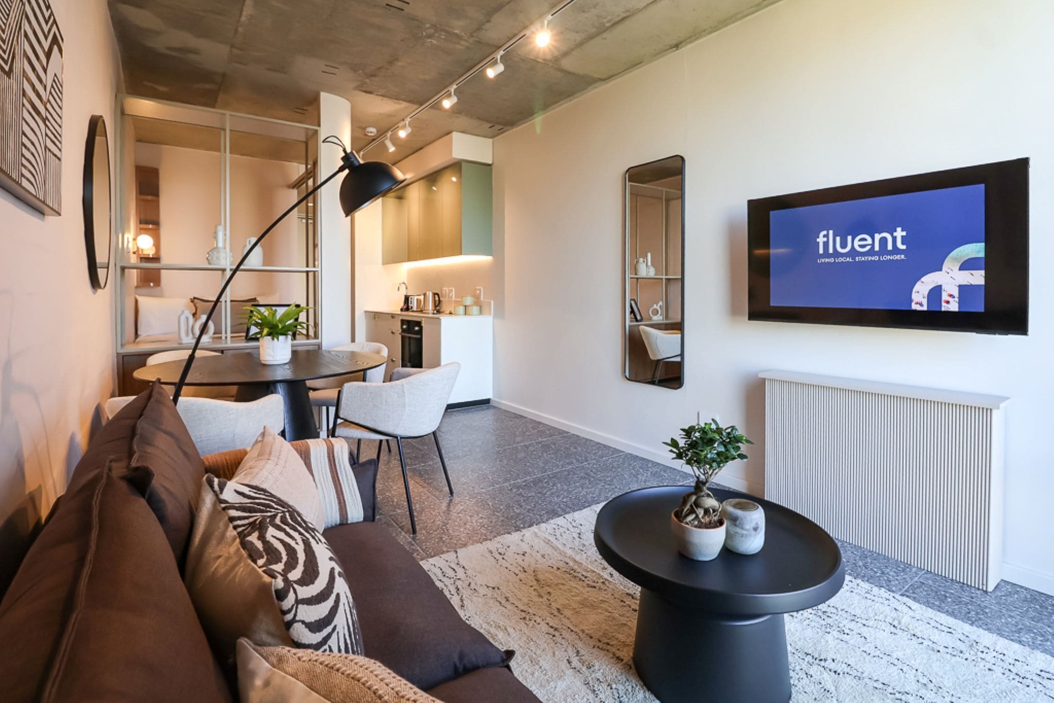 A modern living room with a sofa, a coffee table, and a TV displaying the word 'fluent'.