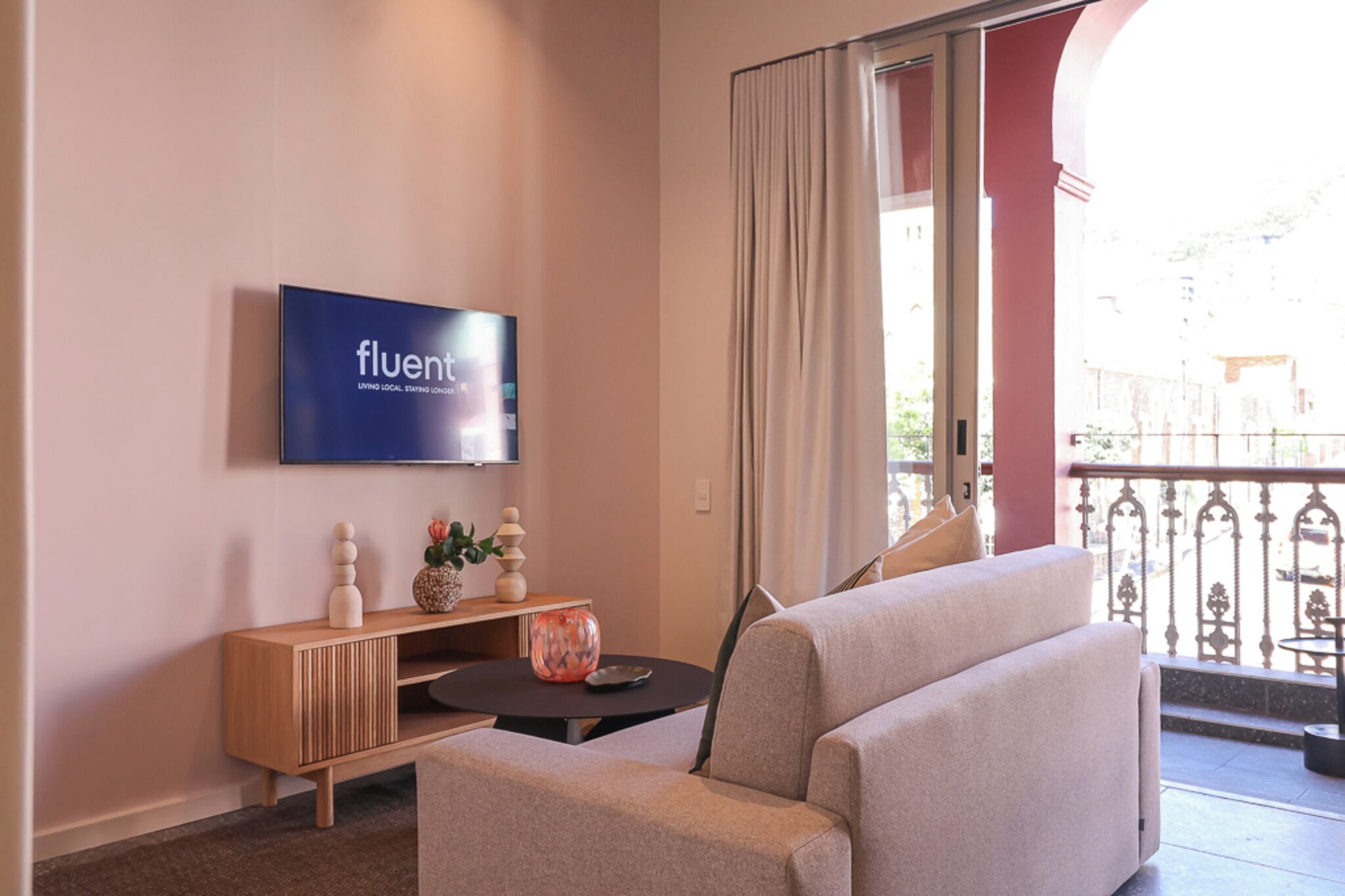 A modern living room with a flat-screen TV, a sofa, a small table, and decorative items.