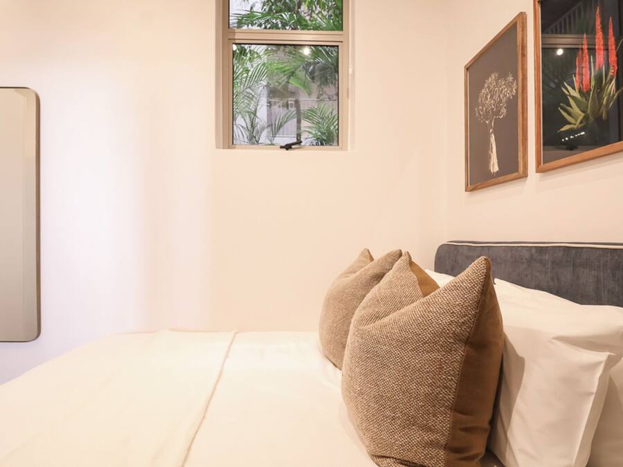 Une chambre à coucher avec un lit, une fenêtre et deux tableaux encadrés accrochés au mur.