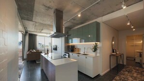 A modern kitchen with a central island, built-in appliances, and a large window. - ONEHUNDRED on M - Fluent Serviced Apartments (Cape Town)