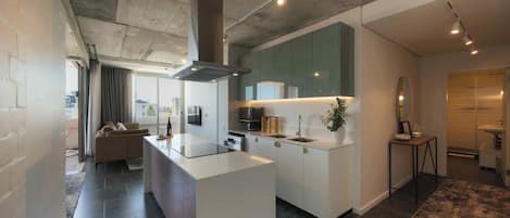 A modern kitchen with a central island, built-in appliances, and a large window.