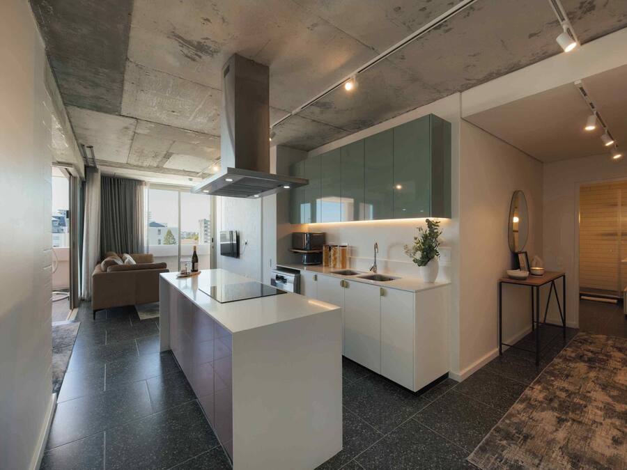 A modern kitchen with a central island, built-in appliances, and a large window.