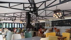 En rymlig restaurang med högt i tak, synliga takbjälkar och en mängd olika sittarrangemang, inklusive bord och stolar.