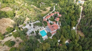 Ett flygbildsbild av ett bostadsområde med en swimmingpool, flera hus och omgivande grönska.