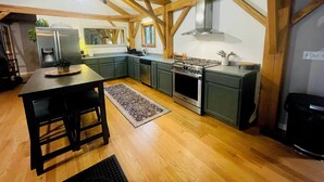 Une cuisine avec des poutres en bois, un réfrigérateur, une cuisinière, un évier et un coin repas avec une table et des chaises.
