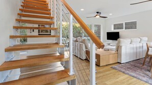 A modern living room with a wooden staircase, a sofa set, and a flat-screen TV. - Sedona Canyon Whisper: A 3BR retreat in Oak Creek Canyon with stunning red rock views. (Sedona)