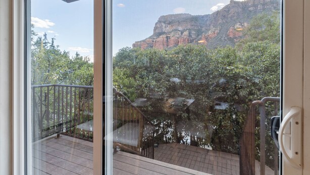 A balcony with a view of a rocky mountain and dense foliage. - Sedona Canyon Whisper: A 3BR retreat in Oak Creek Canyon with stunning red rock views. (Sedona)