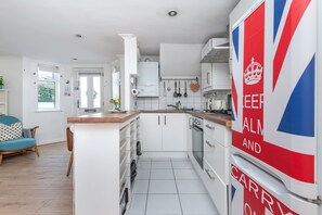 A modern kitchen with white cabinetry, a wooden countertop, and a British flag decoration.