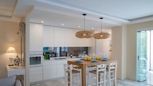 Una cocina moderna con armarios blancos, una mesa de comedor de madera y dos lámparas colgantes.