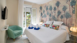 Una habitación de hotel con una cama, una silla, un televisor y un mural de palmeras.