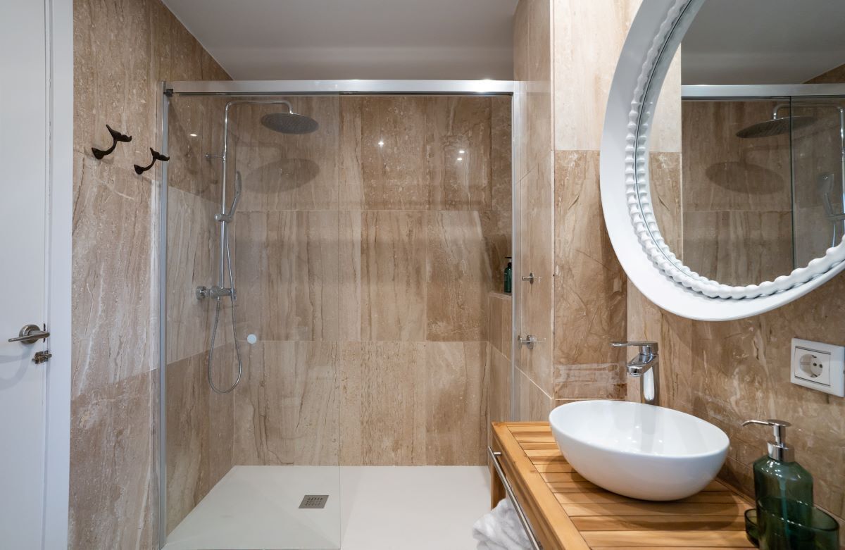 A modern bathroom with a glass-enclosed shower, a wooden vanity with a white sink, and a large mirror.