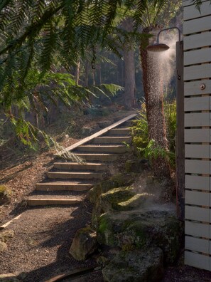 Un escalier en bois menant au sommet d’une colline, entouré de verdure et de rochers.