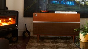 Une pièce avec un poêle à bois, une radio ancienne et un tableau accroché au mur.