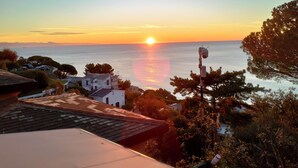A coastal sunset view with buildings and trees in the foreground. - Sea view terrace apartment (Arenzano)