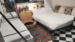 A bedroom with a bed, a small wooden dresser, a wicker basket, and a patterned rug. - Sea view terrace apartment (Arenzano)
