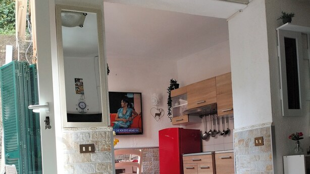 A room with a checkered floor, a red refrigerator, a wooden cabinet, and a wall-mounted air conditioner. - Sea view terrace apartment (Arenzano)