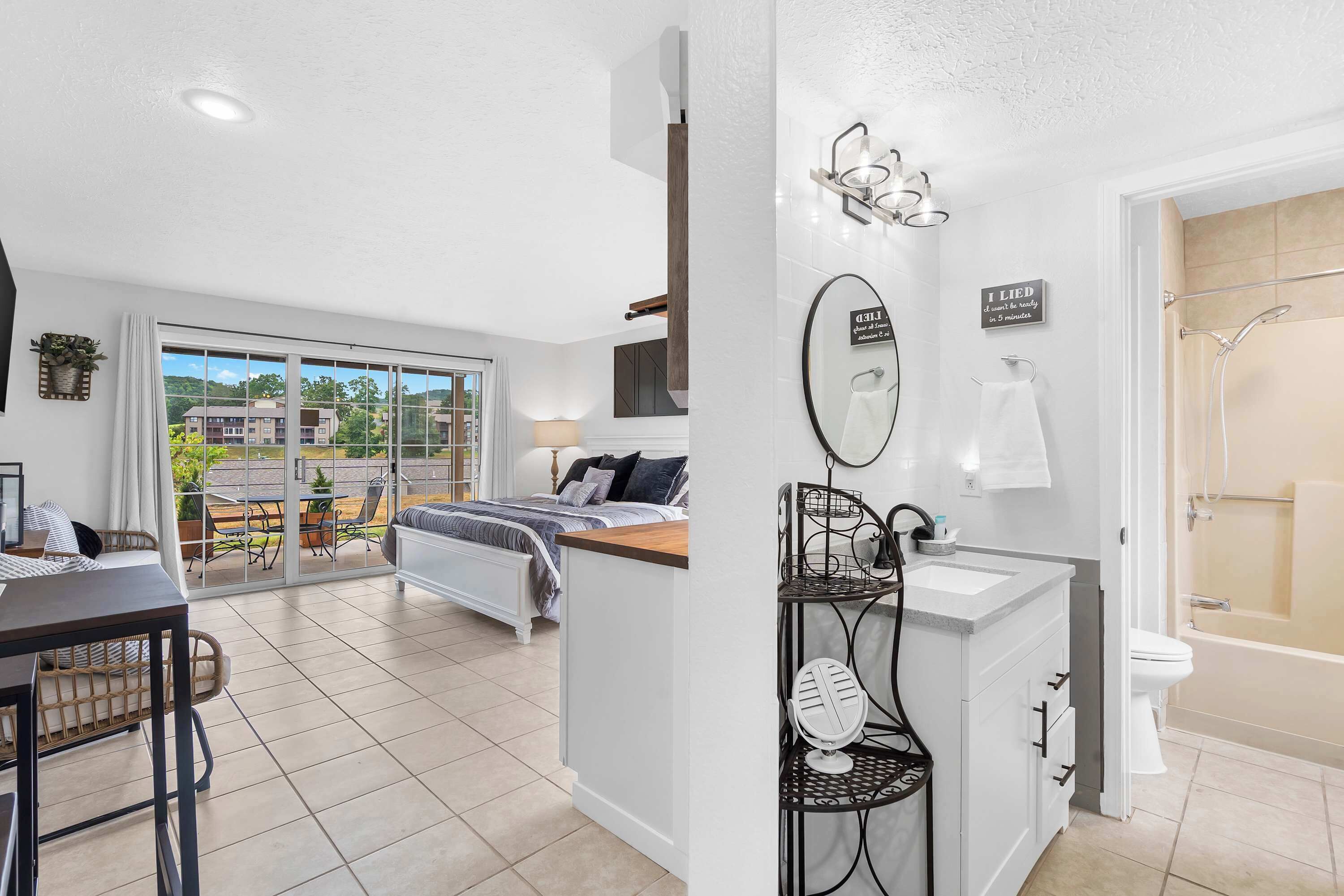Une chambre moderne comprenant un lit, une table de chevet, un miroir et une salle de bain avec des toilettes et une douche.