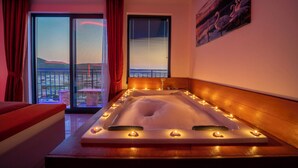 A spa room with a large bathtub, red curtains, and a view of the cityscape. - Villa Sunlegend (Yeşilköy)