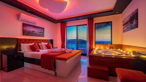 A modern hotel room with a large bed, a jacuzzi, and a city view. - Villa Sunlegend (Yeşilköy)
