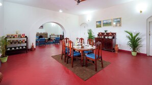 A dining area with a round table, chairs, a ceiling fan, and potted plants.