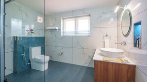 A modern bathroom with a glass shower enclosure, a toilet, a sink with a wooden vanity, and a mirror.