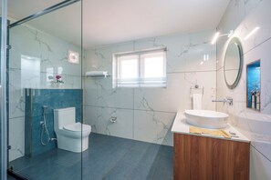 A modern bathroom with a glass shower enclosure, a toilet, a sink with a wooden vanity, and a mirror.