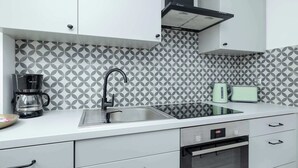 A modern kitchen with a stainless steel sink, a coffee maker, a toaster, and a built-in oven.