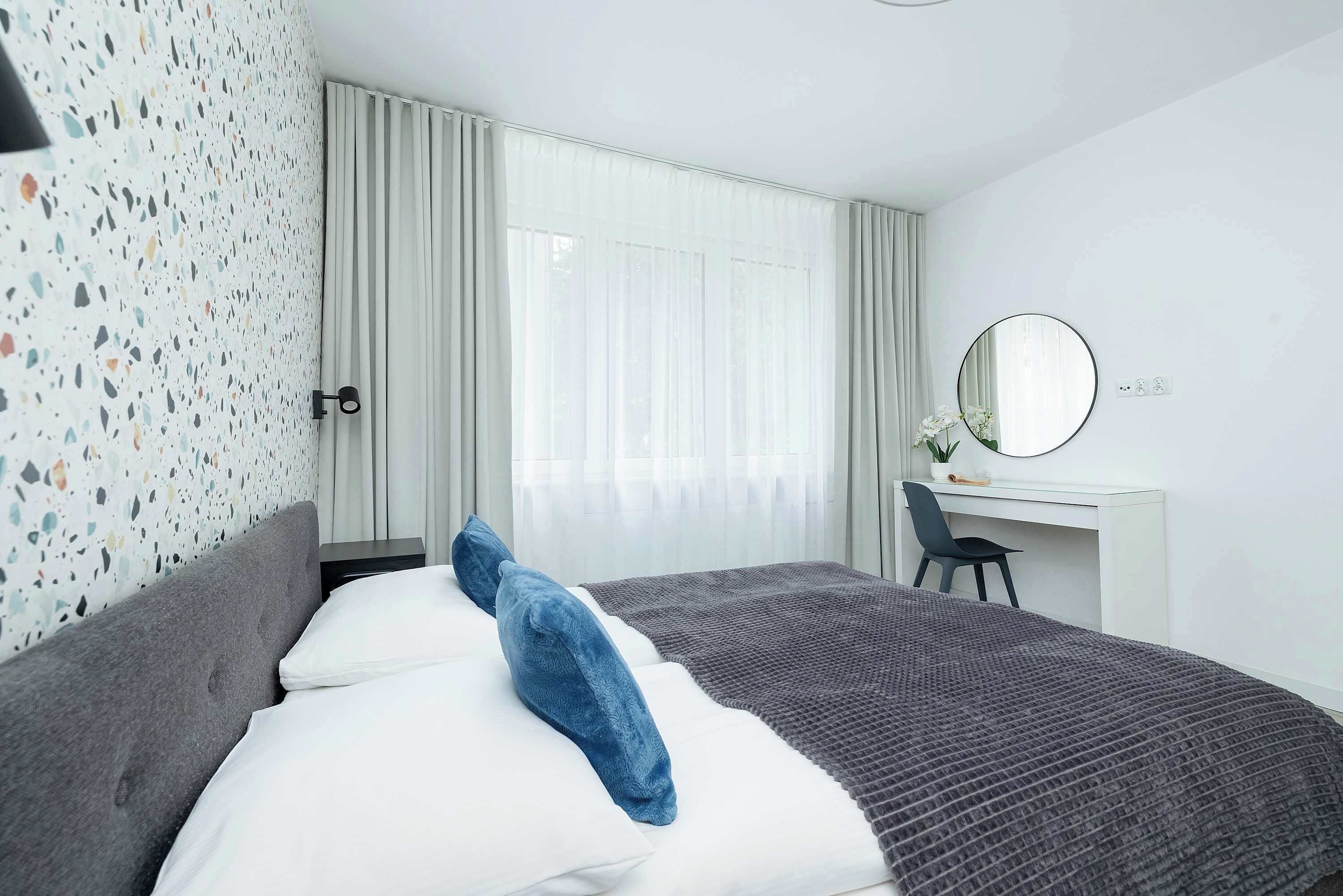 Une chambre d’hôtel moderne, équipée d’un lit, d’un bureau et d’une grande fenêtre.
