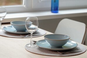 A dining table with two blue bowls and a wine glass, set on a placemat.