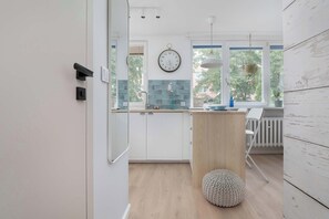 A modern kitchen with white cabinets, a wooden countertop, and a round stool.