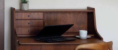 A wooden desk with a laptop, a cup, and a small plant.