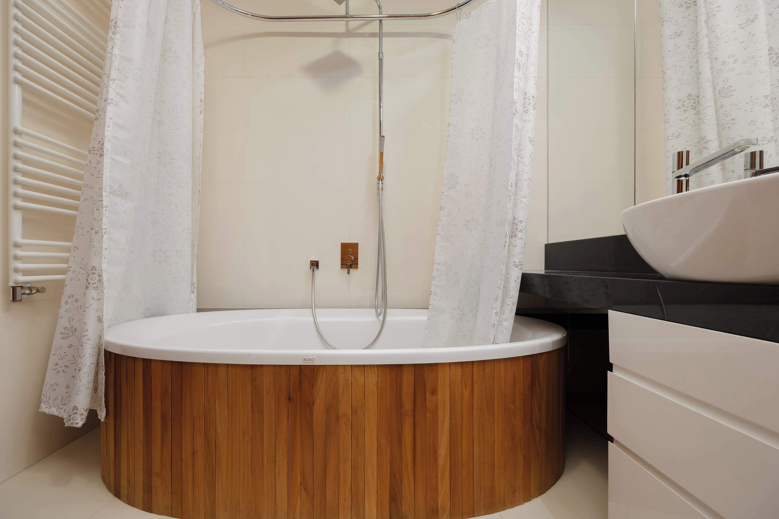 A modern bathroom with a wooden bathtub, a shower, and a sink.