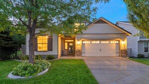 A two-story house with a garage, a well-maintained lawn, and a stone accent wall.