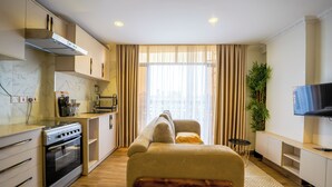 A modern living room with a sofa, a television, and a kitchen area with an oven. - Qusini Kenya (Nairobi)