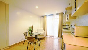Un espacio habitable compacto con zona de comedor, sofá, pequeña mesa y kitchenette.