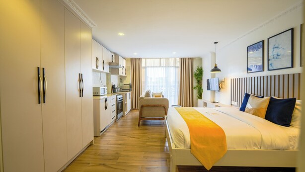 Habitación de hotel moderna con una cama grande, kitchenette y vistas a la ciudad.
