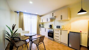 Una cocina compacta con zona de comedor, que incluye una mesa, sillas, un refrigerador, un horno y un microondas.
