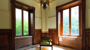 A room with a green chair, wooden paneling, large windows, and a marble floor. - Villa Magnolia (Castellammare di Stabia)
